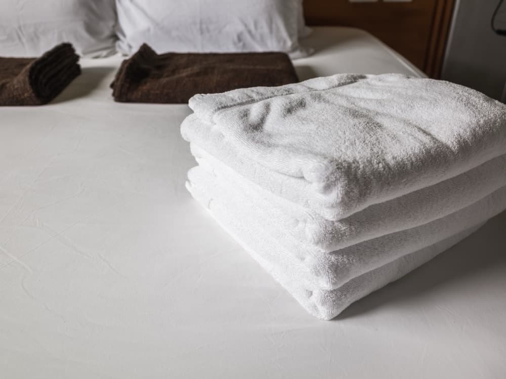 Toallas limpias y dobladas sobre la cama hecha de una habitación de hotel