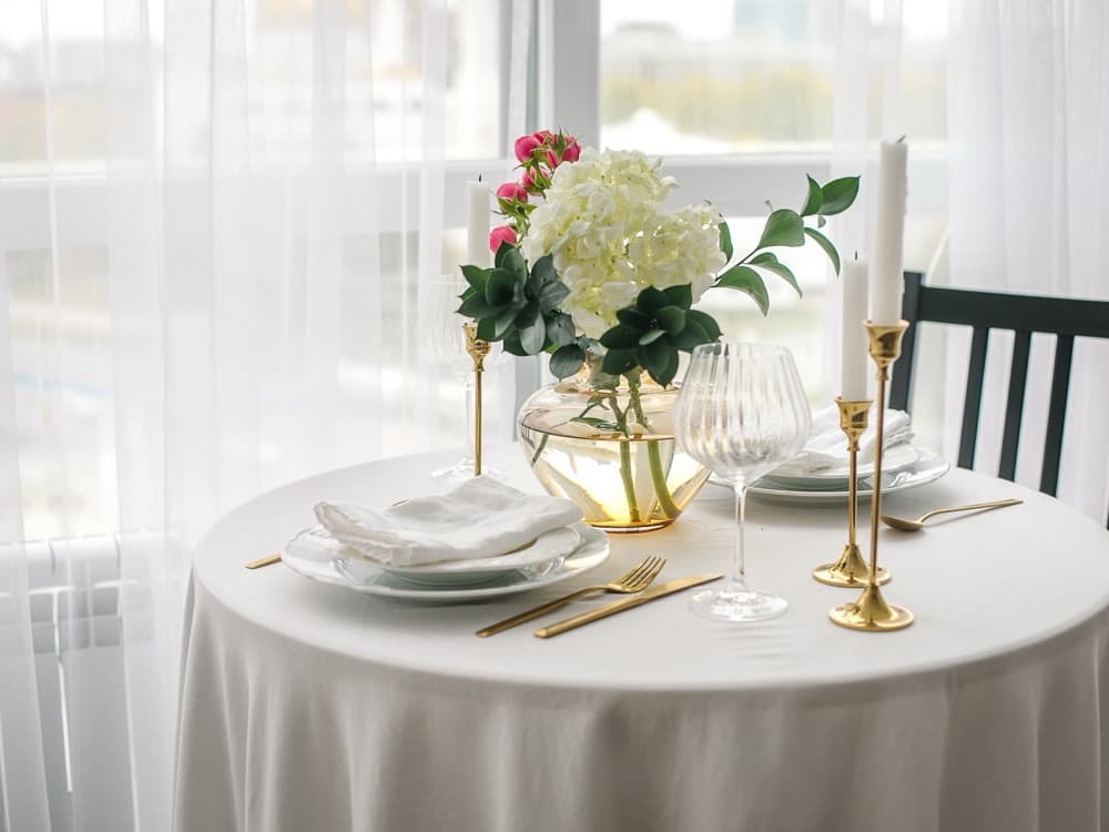 Mesa de restaurante montada con mantel y servilleta de tela blancos